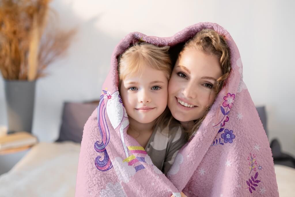 A heartwarming moment between a mother and daughter wrapped in a soft unicorn-themed organic cotton towel. The plush pink towel features a charming unicorn with delicate floral accents, providing warmth and comfort. Made from 100% premium organic cotton, this ultra-absorbent towel by Khelo is gentle on the skin, making it perfect for kids’ bath time, beach days, and cozy cuddles. Its breathable, quick-drying fabric ensures long-lasting use with a fade-resistant design for up to 500 washes.